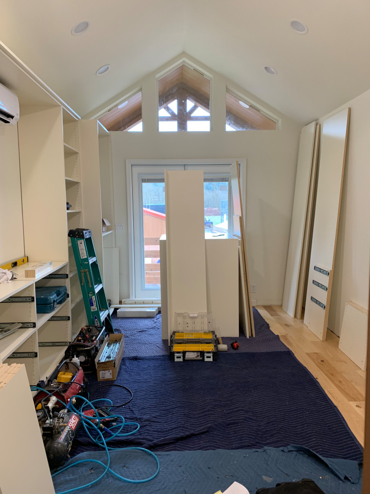 This is an example of a mid-sized traditional gender-neutral walk-in wardrobe in Other with shaker cabinets, beige cabinets, medium hardwood floors and yellow floor.