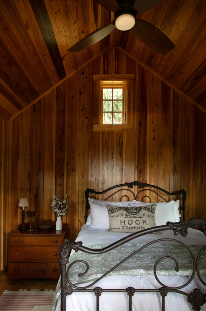 Idee per una camera da letto country di medie dimensioni con pareti marroni, pavimento in legno massello medio, nessun camino, pavimento marrone, soffitto in legno e pareti in legno