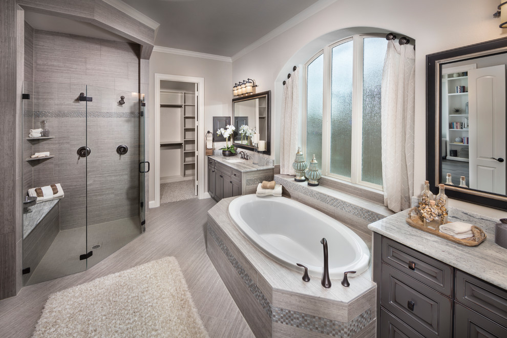 Traditional bathroom in Houston with a drop-in tub, a corner shower, gray tile, grey walls, an undermount sink, grey floor and a hinged shower door.