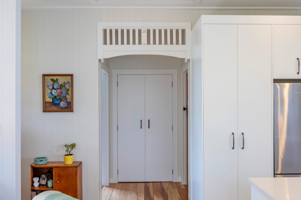 Foto de recibidores y pasillos clásicos pequeños con paredes blancas, suelo de madera en tonos medios y machihembrado