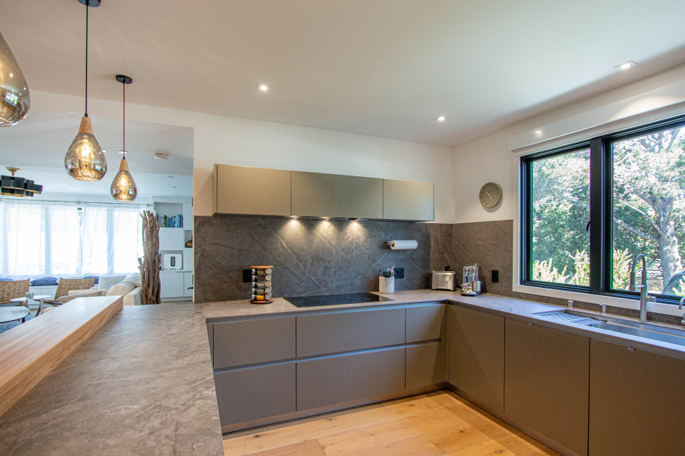 Contemporary u-shaped kitchen in Other with an undermount sink, flat-panel cabinets, grey splashback, medium hardwood floors, no island and grey benchtop.