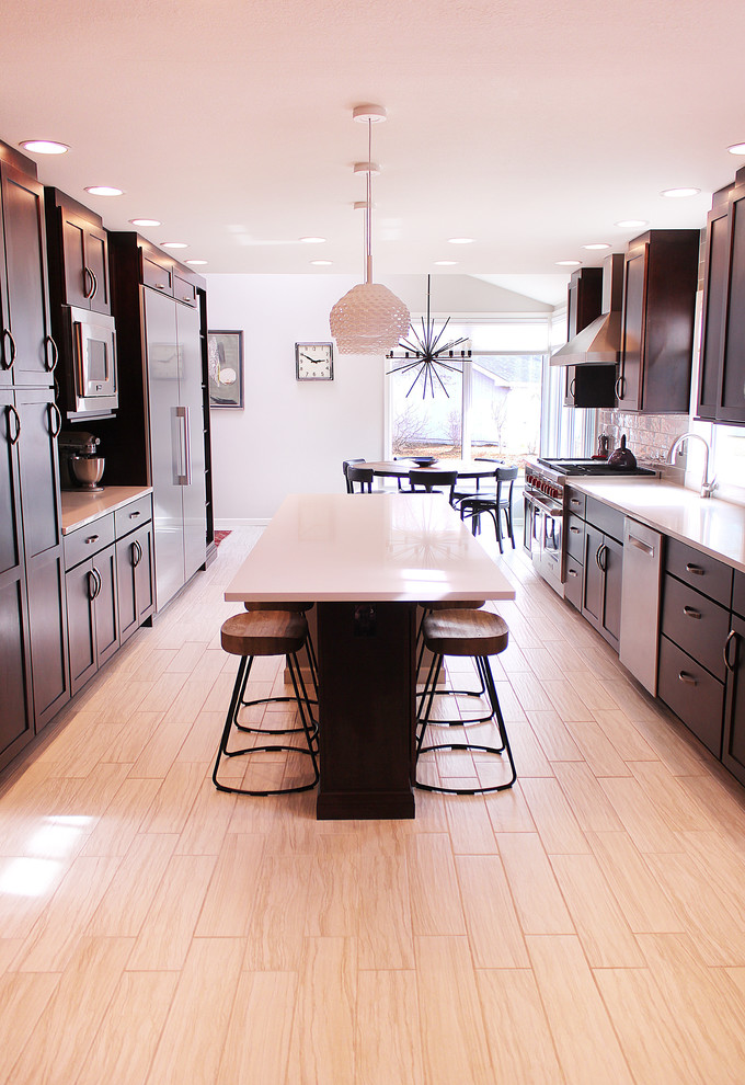 Photo of a large contemporary galley eat-in kitchen in Other with an undermount sink, recessed-panel cabinets, black cabinets, white splashback, stainless steel appliances, light hardwood floors and with island.