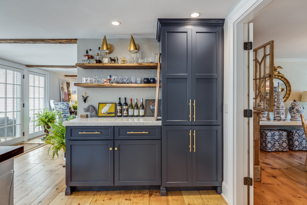 Design ideas for a transitional single-wall home bar in Boston with shaker cabinets, blue cabinets, medium hardwood floors, brown floor and white benchtop.
