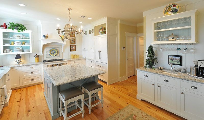 Photo of a mid-sized country u-shaped eat-in kitchen in Atlanta with an undermount sink, louvered cabinets, white cabinets, granite benchtops, white appliances, light hardwood floors and with island.