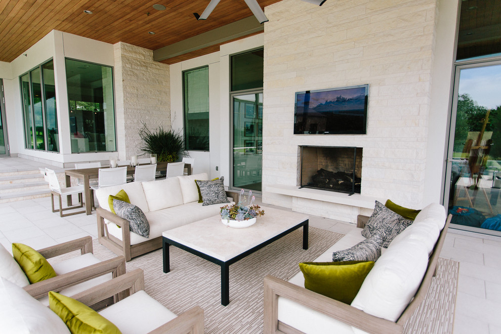 Expansive modern backyard patio in Austin with an outdoor kitchen, natural stone pavers and a roof extension.