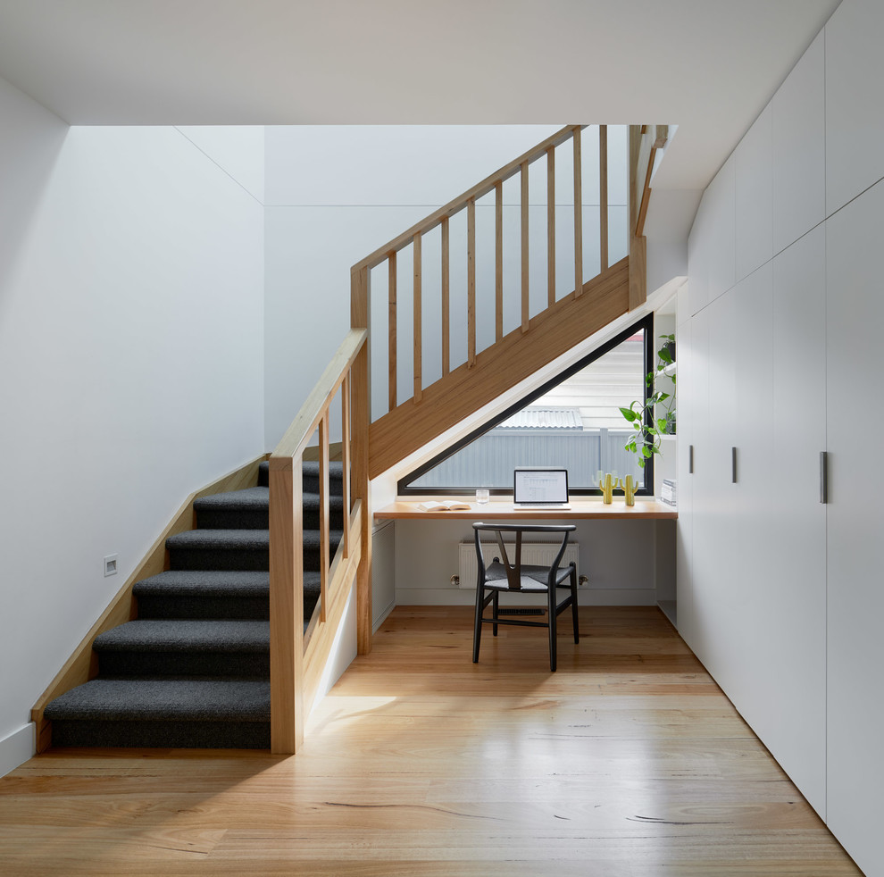 Photo of a large contemporary carpeted l-shaped staircase in Melbourne with carpet risers and wood railing.