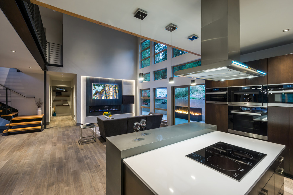 Photo of a large modern l-shaped open plan kitchen in Other with an undermount sink, flat-panel cabinets, dark wood cabinets, quartz benchtops, white splashback, glass tile splashback, stainless steel appliances, medium hardwood floors and with island.