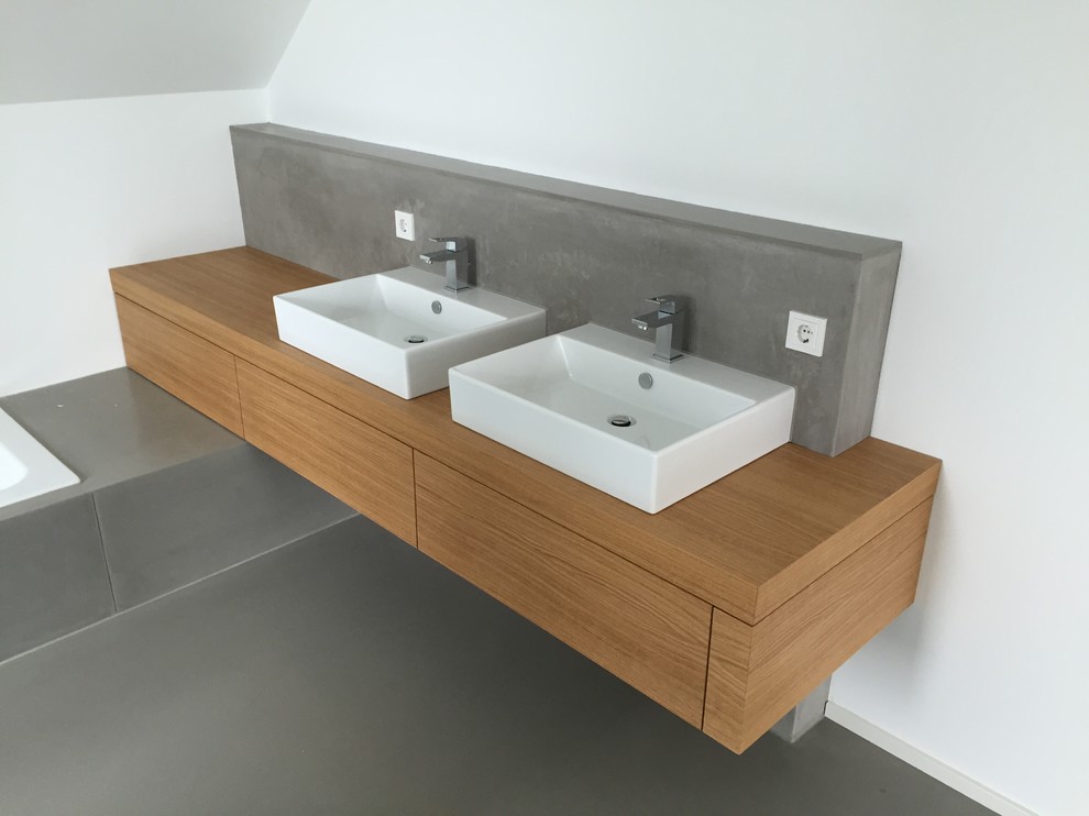 Inspiration for a mid-sized modern 3/4 bathroom in Cologne with flat-panel cabinets, dark wood cabinets, an alcove tub, an alcove shower, a wall-mount toilet, beige tile, glass tile, white walls, a vessel sink and wood benchtops.