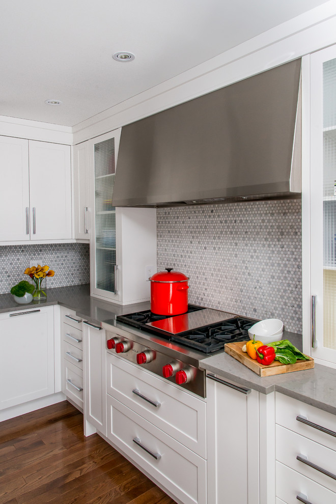 Example of a large transitional l-shaped medium tone wood floor eat-in kitchen design in Calgary with an undermount sink, shaker cabinets, white cabinets, quartz countertops, multicolored backsplash, mosaic tile backsplash, stainless steel appliances and an island