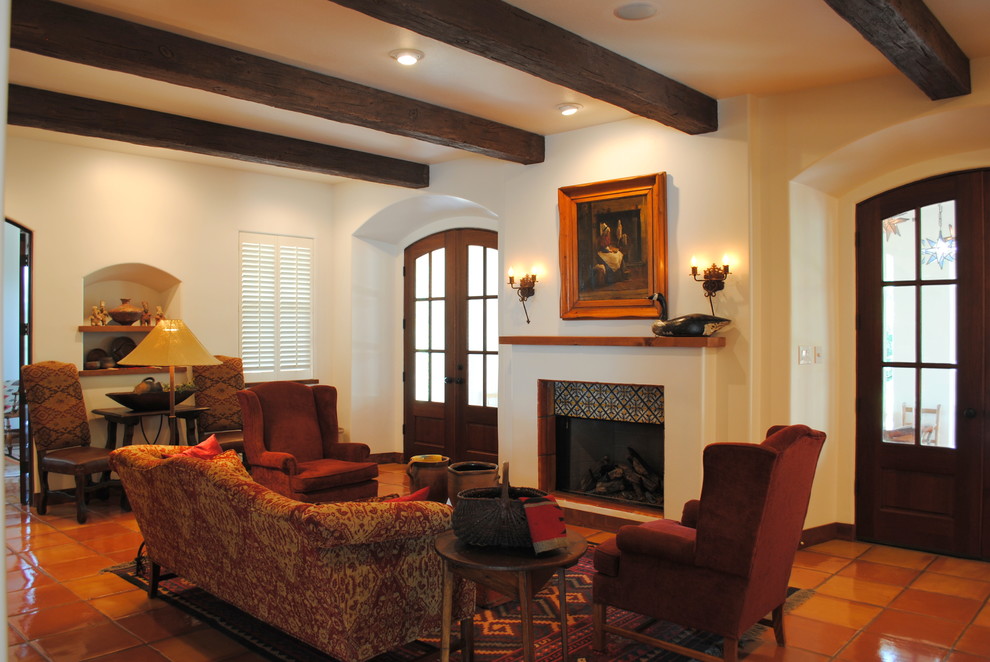 This is an example of a large formal enclosed living room in Austin with white walls, terra-cotta floors, a standard fireplace, no tv and a tile fireplace surround.