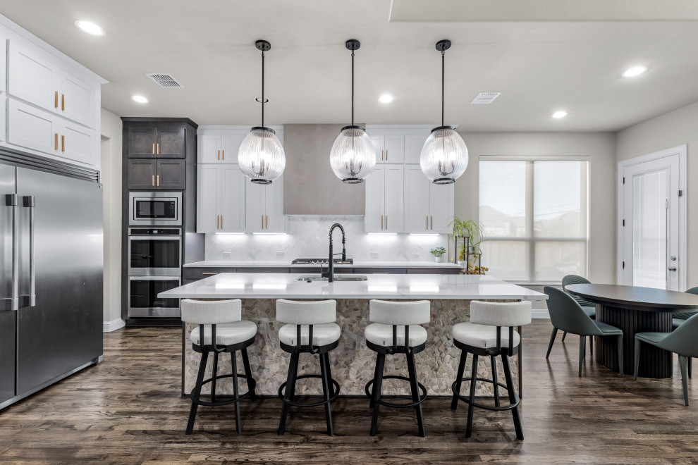 Inspiration for a transitional l-shaped dark wood floor and brown floor eat-in kitchen remodel in Dallas with an undermount sink, shaker cabinets, white cabinets, white backsplash, stainless steel appliances, an island and white countertops