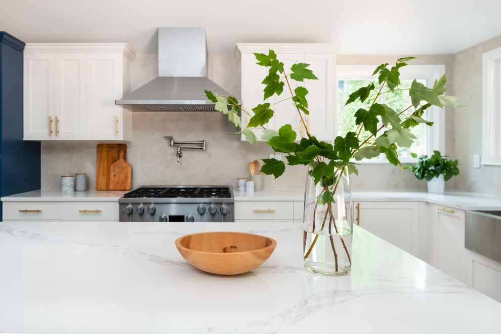 This is an example of a mid-sized contemporary u-shaped kitchen in Seattle with a farmhouse sink, shaker cabinets, white cabinets, white splashback, ceramic splashback, stainless steel appliances, porcelain floors, with island, white floor, white benchtop and quartzite benchtops.