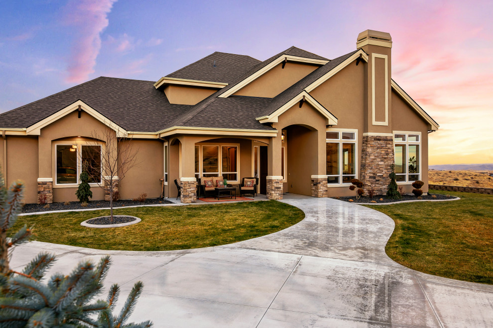 Large country two-storey stucco brown house exterior in Boise with a hip roof and a shingle roof.