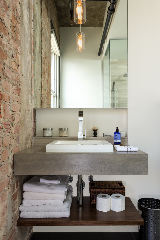 This is an example of an industrial bathroom in Houston with concrete benchtops and white walls.