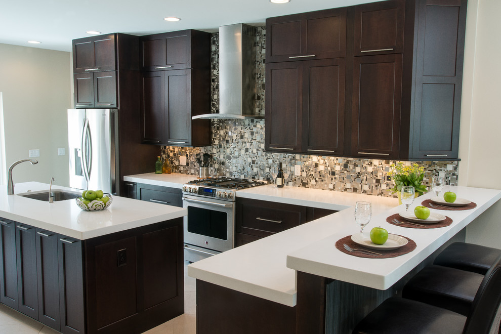 Design ideas for a mid-sized traditional l-shaped eat-in kitchen in Tampa with an undermount sink, recessed-panel cabinets, dark wood cabinets, quartz benchtops, grey splashback, mosaic tile splashback, stainless steel appliances, ceramic floors, with island and beige floor.
