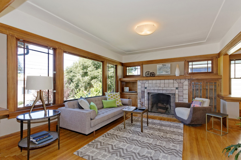 Photo of an arts and crafts living room in San Francisco with white walls, medium hardwood floors, a standard fireplace and a tile fireplace surround.