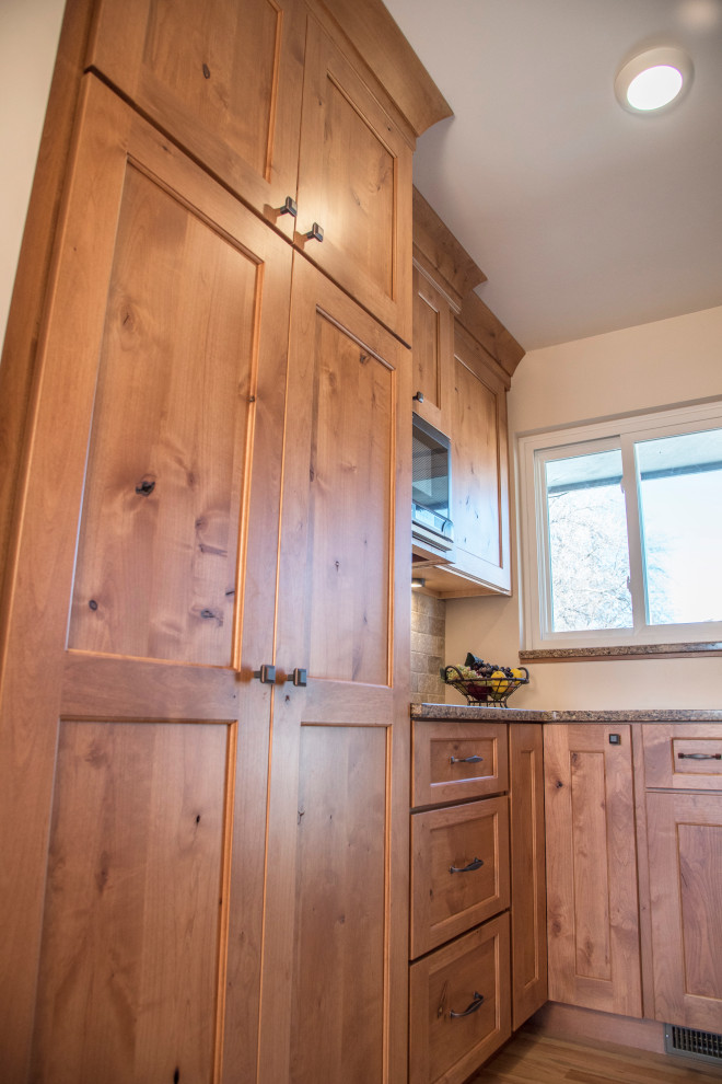 Example of a mid-sized mountain style galley medium tone wood floor and brown floor eat-in kitchen design in Denver with an undermount sink, shaker cabinets, medium tone wood cabinets, quartz countertops, gray backsplash, stone tile backsplash, black appliances, no island and brown countertops