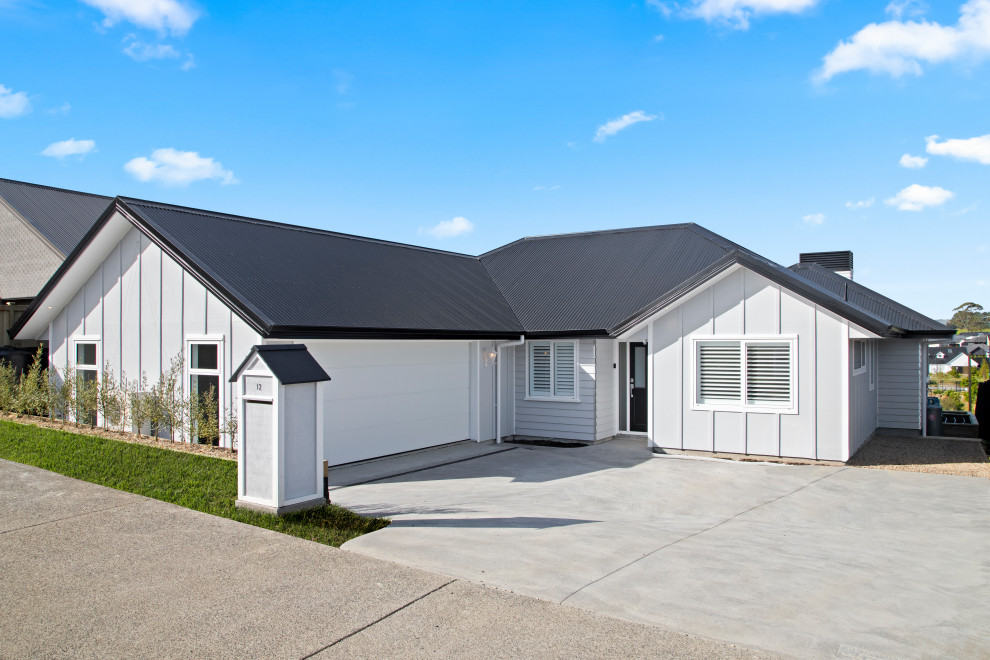 Inspiration for a medium sized and gey coastal bungalow detached house in Auckland with mixed cladding, a pitched roof, a metal roof, a black roof and board and batten cladding.