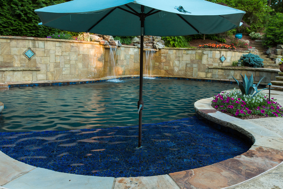 Large traditional backyard custom-shaped natural pool in Atlanta with a water feature and stamped concrete.