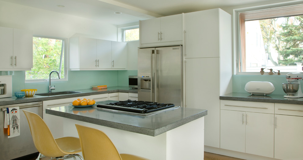 Large contemporary l-shaped eat-in kitchen in Boston with flat-panel cabinets, white cabinets, quartz benchtops, blue splashback, glass sheet splashback, with island, a drop-in sink, stainless steel appliances and light hardwood floors.