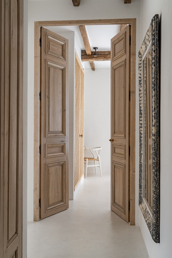 Foto di un ingresso o corridoio mediterraneo di medie dimensioni con pareti bianche, pavimento in cemento, pavimento beige e travi a vista