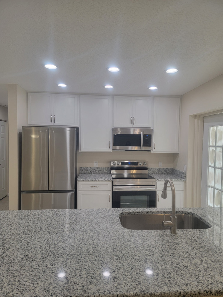 Mid-sized galley eat-in kitchen photo with an undermount sink, shaker cabinets, white cabinets, quartz countertops, a peninsula and gray countertops