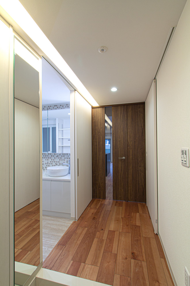 Exemple d'une petite entrée montagne avec un couloir, un mur marron, un sol en bois brun, une porte simple, une porte en bois foncé, un sol marron, un plafond en papier peint et du papier peint.