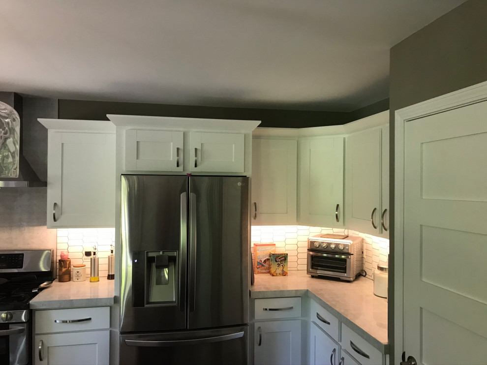 This is an example of a medium sized modern u-shaped kitchen pantry in Detroit with shaker cabinets, white cabinets, concrete worktops, white splashback, metro tiled splashback, stainless steel appliances, an island, grey worktops, a submerged sink, dark hardwood flooring and black floors.