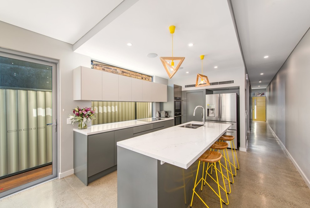 Design ideas for a mid-sized contemporary galley eat-in kitchen in Sydney with a double-bowl sink, concrete floors, with island, flat-panel cabinets, grey cabinets, quartz benchtops, window splashback, black appliances and white benchtop.