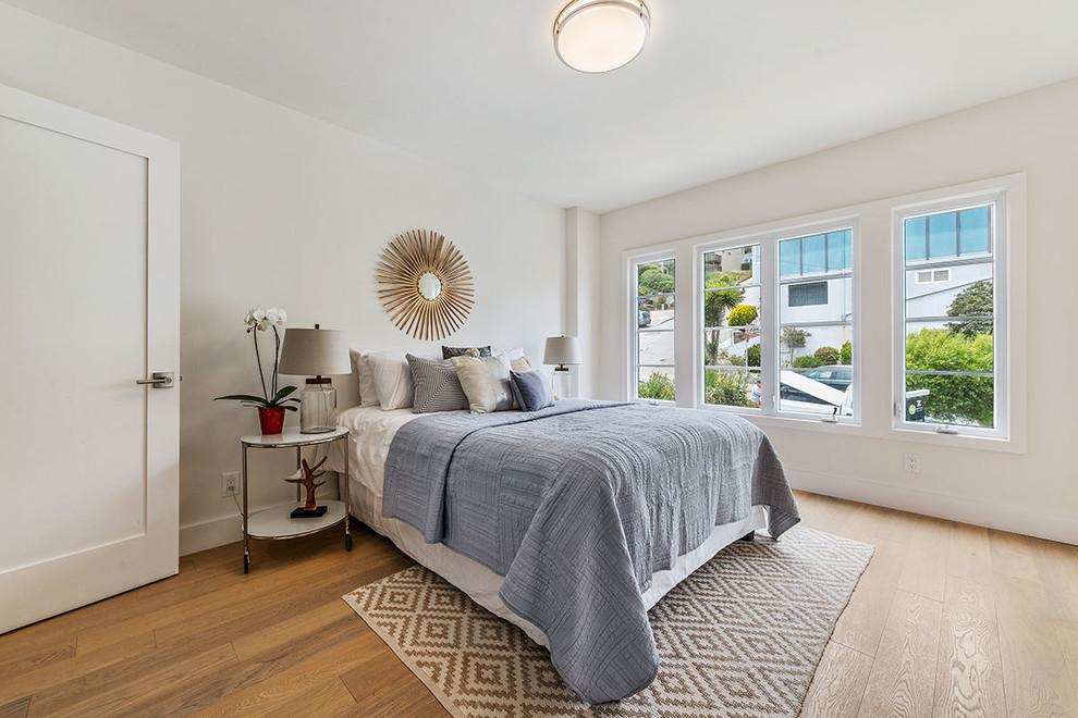 This is an example of a small transitional guest bedroom in San Francisco with white walls, light hardwood floors and no fireplace.
