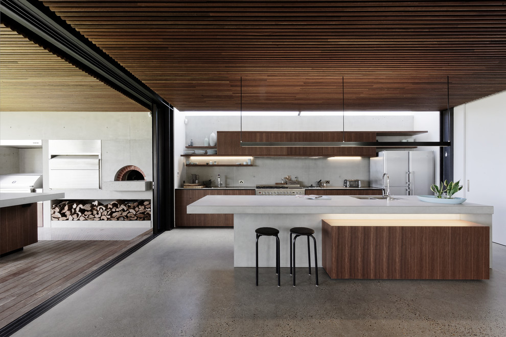 Inspiration for a mid-sized contemporary galley open plan kitchen in Central Coast with an undermount sink, beaded inset cabinets, dark wood cabinets, concrete benchtops, grey splashback, stainless steel appliances, concrete floors, with island, grey floor and grey benchtop.