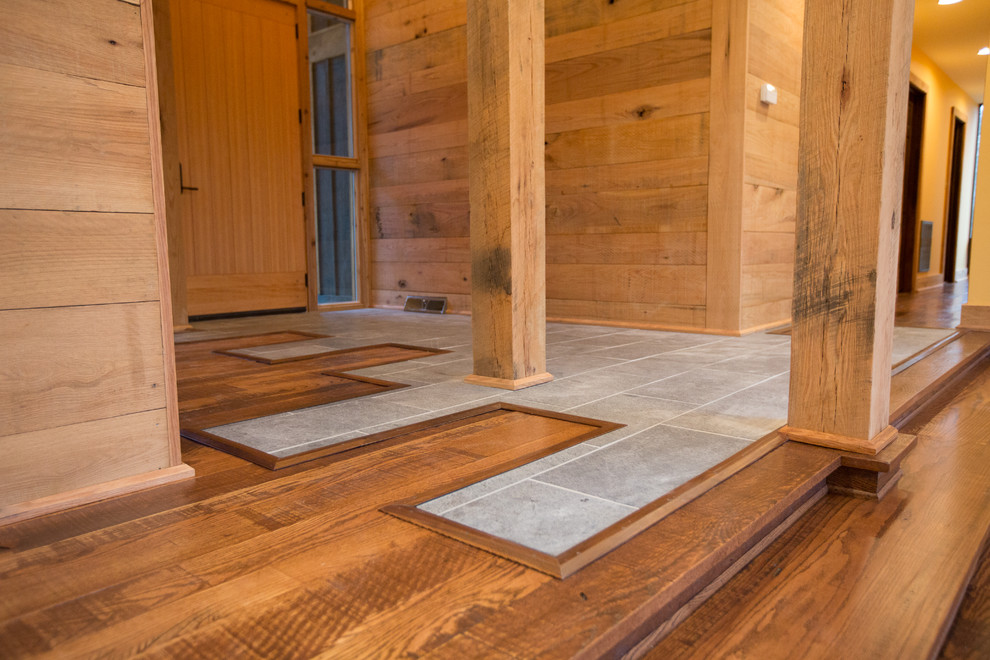Example of a large mountain style medium tone wood floor foyer design with brown walls and a medium wood front door