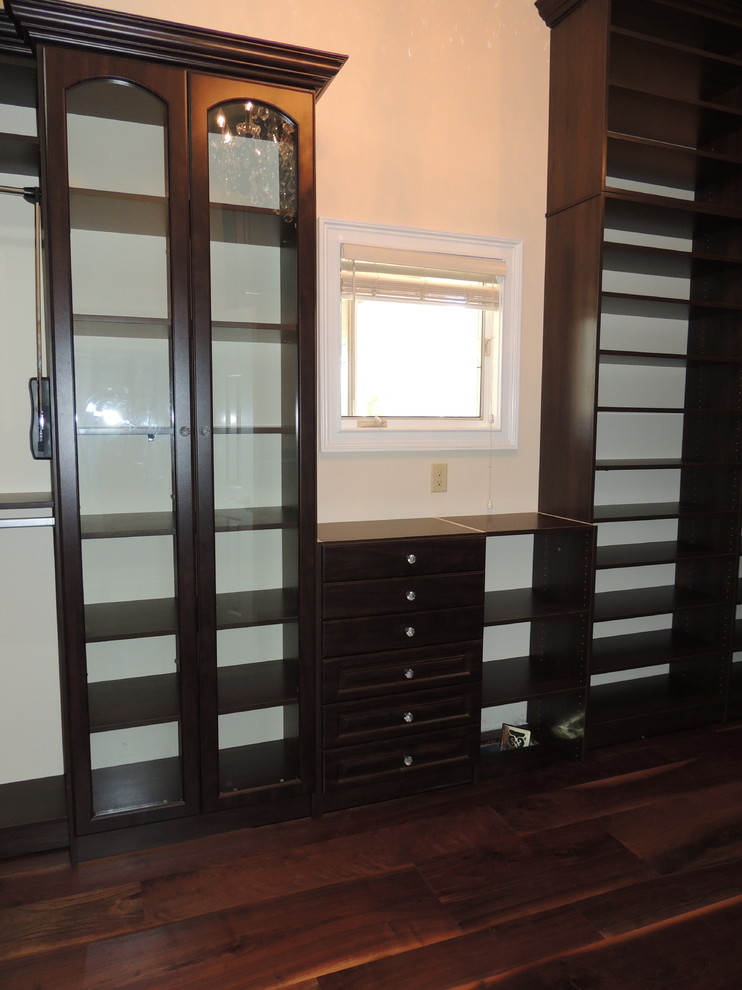 Inspiration for a large traditional gender-neutral walk-in wardrobe in Philadelphia with raised-panel cabinets, brown cabinets and dark hardwood floors.