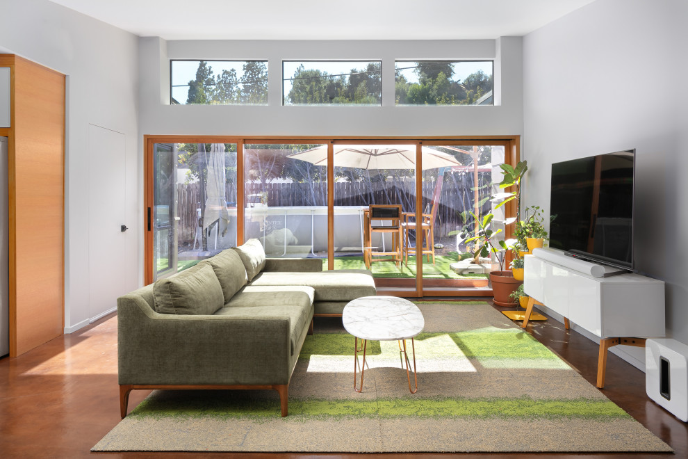 Foto på ett mellanstort retro allrum med öppen planlösning, med grå väggar, betonggolv, en fristående TV och brunt golv