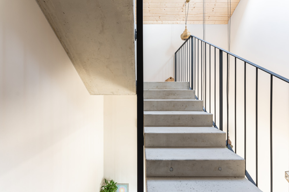 This is an example of an expansive modern concrete u-shaped metal railing staircase in Frankfurt with concrete risers.