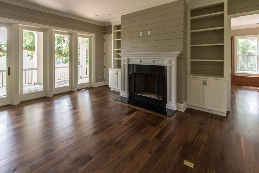 This is an example of a traditional formal open concept living room in Charleston with beige walls, dark hardwood floors, a standard fireplace and a wood fireplace surround.