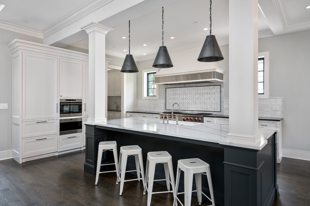 Photo of a traditional kitchen in Chicago with a drop-in sink, shaker cabinets, white cabinets, white splashback, subway tile splashback, stainless steel appliances, dark hardwood floors and with island.