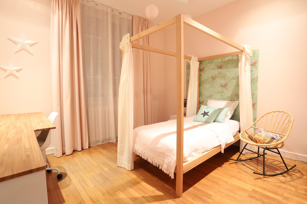 This is an example of a mid-sized contemporary kids' room for girls in Nice with pink walls, light hardwood floors and wallpaper.