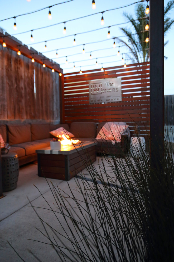 Design ideas for a small modern courtyard patio in San Luis Obispo with a fire feature, concrete slab and a pergola.