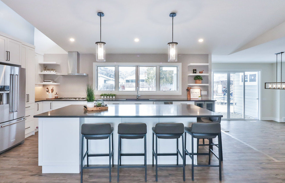 Large transitional l-shaped vinyl floor and brown floor open concept kitchen photo with an undermount sink, flat-panel cabinets, white cabinets, quartz countertops, gray backsplash, porcelain backsplash, stainless steel appliances and an island