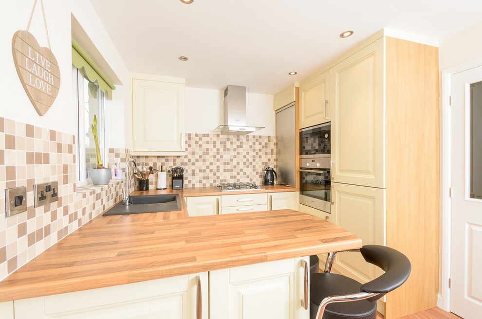 This is an example of a small traditional l-shaped eat-in kitchen in Other with light wood cabinets, wood benchtops, brown splashback, terra-cotta splashback, panelled appliances, linoleum floors and a peninsula.