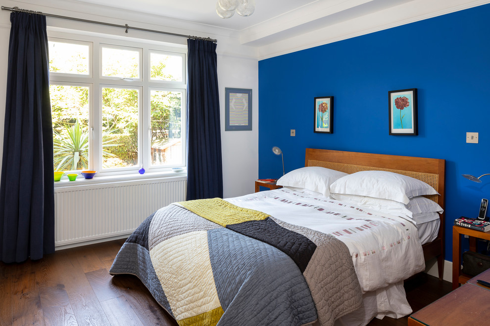 Inspiration for a mid-sized eclectic master bedroom in London with blue walls, dark hardwood floors, no fireplace and brown floor.