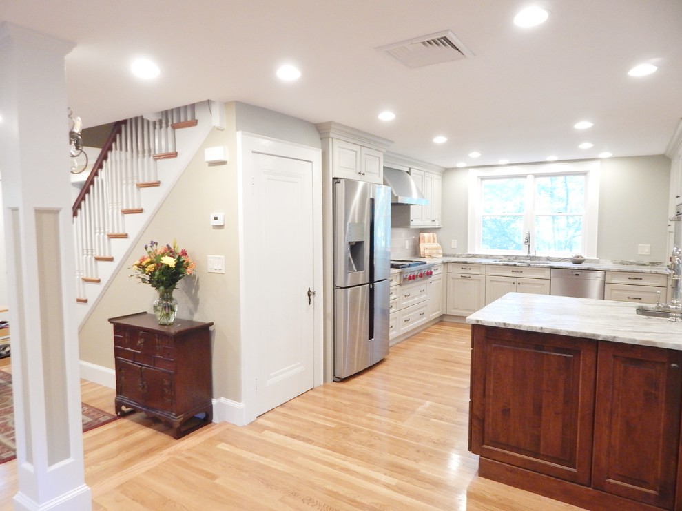 Open concept kitchen - mid-sized transitional l-shaped light wood floor open concept kitchen idea in Boston with an undermount sink, raised-panel cabinets, white cabinets, quartzite countertops, stainless steel appliances and an island