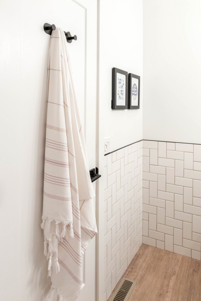 Idéer för ett litet modernt vit badrum, med skåp i shakerstil, svarta skåp, ett badkar i en alkov, en dusch/badkar-kombination, en toalettstol med hel cisternkåpa, vit kakel, keramikplattor, vita väggar, vinylgolv, ett undermonterad handfat, bänkskiva i akrylsten, brunt golv och dusch med duschdraperi