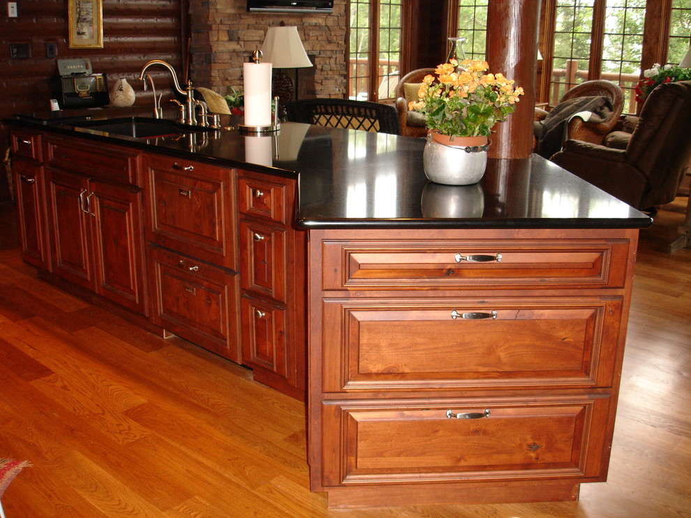 Open concept kitchen - mid-sized rustic l-shaped beige floor open concept kitchen idea with an undermount sink, raised-panel cabinets, medium tone wood cabinets, granite countertops and a peninsula