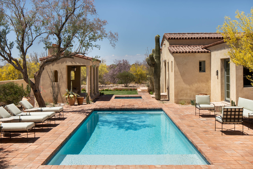 Large mediterranean backyard rectangular lap pool in Phoenix with brick pavers and a hot tub.