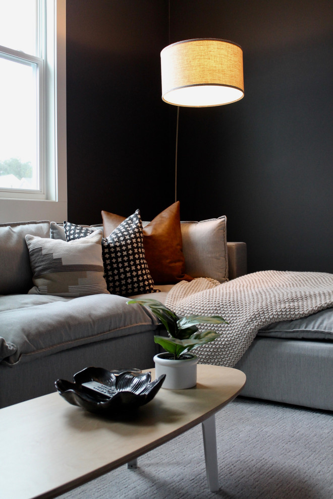 Inredning av ett lantligt stort öppen hemmabio, med svarta väggar, heltäckningsmatta, en väggmonterad TV och grått golv