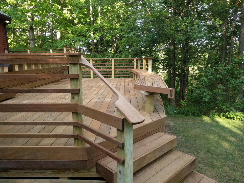 Large modern backyard and ground level deck in Boston with wood railing.