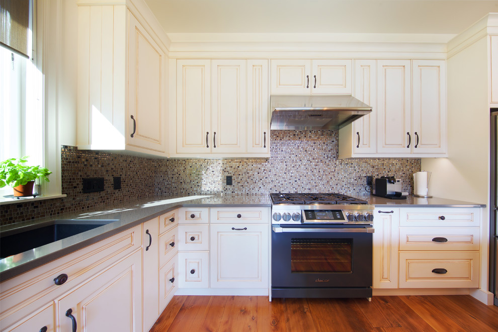 Mid-sized mountain style galley medium tone wood floor open concept kitchen photo in Vancouver with an undermount sink, louvered cabinets, white cabinets, multicolored backsplash, ceramic backsplash, stainless steel appliances and an island
