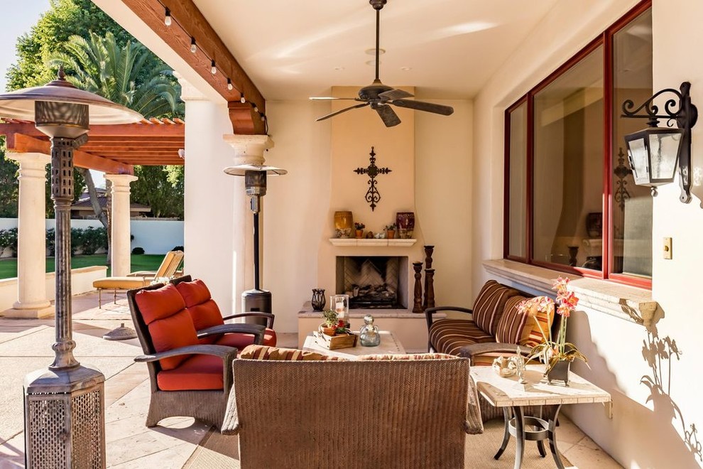 Inspiration for a mediterranean backyard patio in Phoenix with tile, a roof extension and with fireplace.
